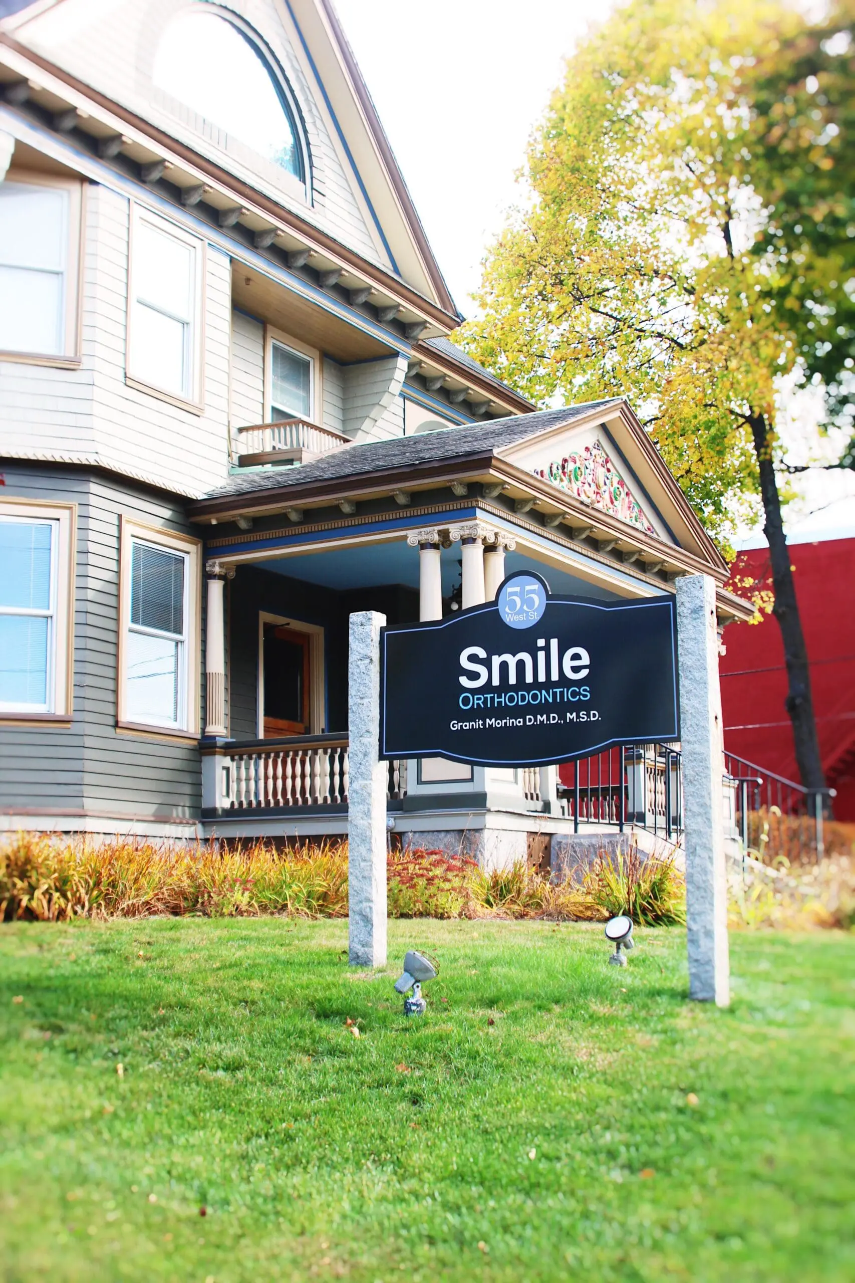 A two-story house with a porch, located in Leominster, MA, displays a "Smile Orthodontics Grant Marino, D.M.D., M.S.D." sign on its grassy front lawn.
