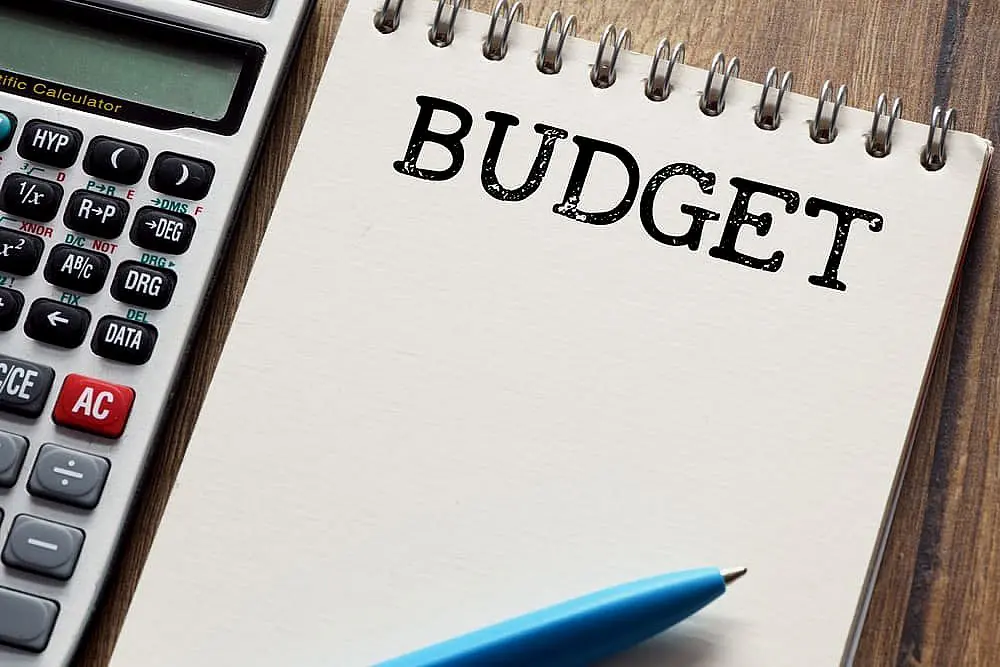 A calculator and blue pen lie beside a notepad marked "BUDGET" on the wooden surface, mapping out your braces payment plan in Leominster and Gardner, MA