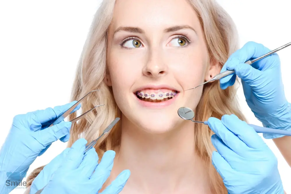 Orthodontist examining a young woman with braces during a dental checkup – Braces for Overbite in Leominster and Gardner, MA