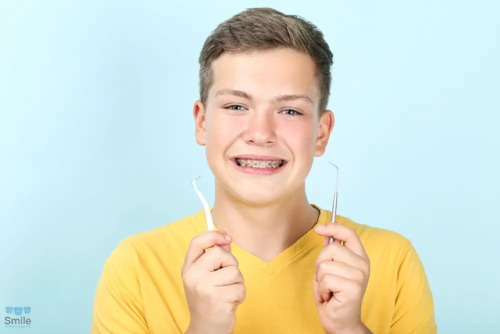 young man with metal braces toothbrush dentist tool - How to Floss with Braces in Leominster and Gardner, MA