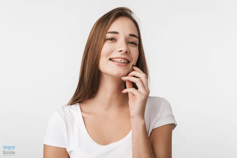 attractive young woman with metal braces standing - Clear Braces vs Metal Braces in Leominster and Gardner, MA