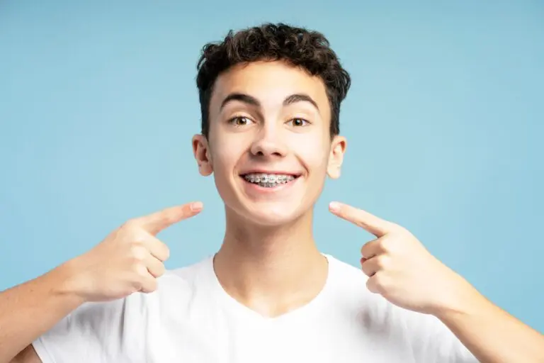 excited smiling boy teenager pointing fingers his metal braces - How to Clean Braces in Leominster, MA